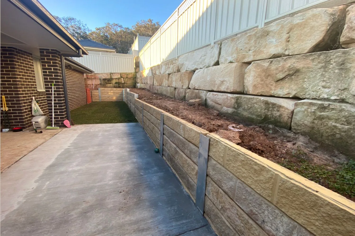 Concrete sleeper retaining wall along a side path below sandstone blocks