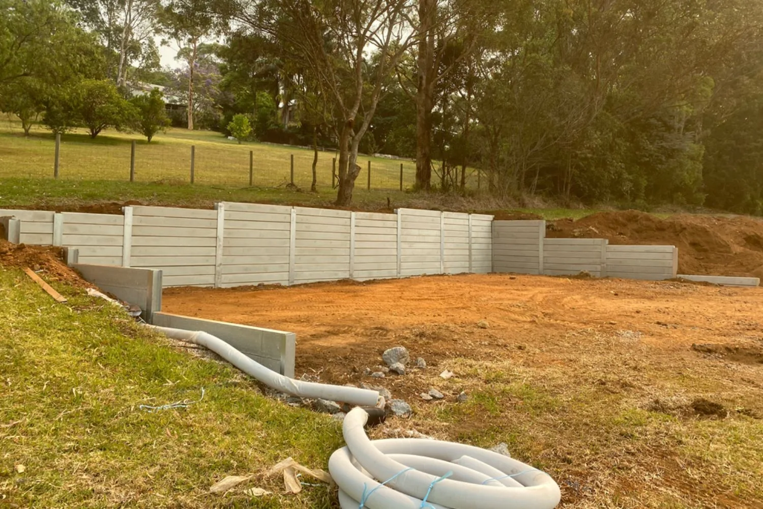 Concrete sleeper retaining wall with drainage pipe during installation