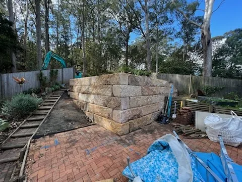 Sandstone block retaining wall under construction beside a paved path