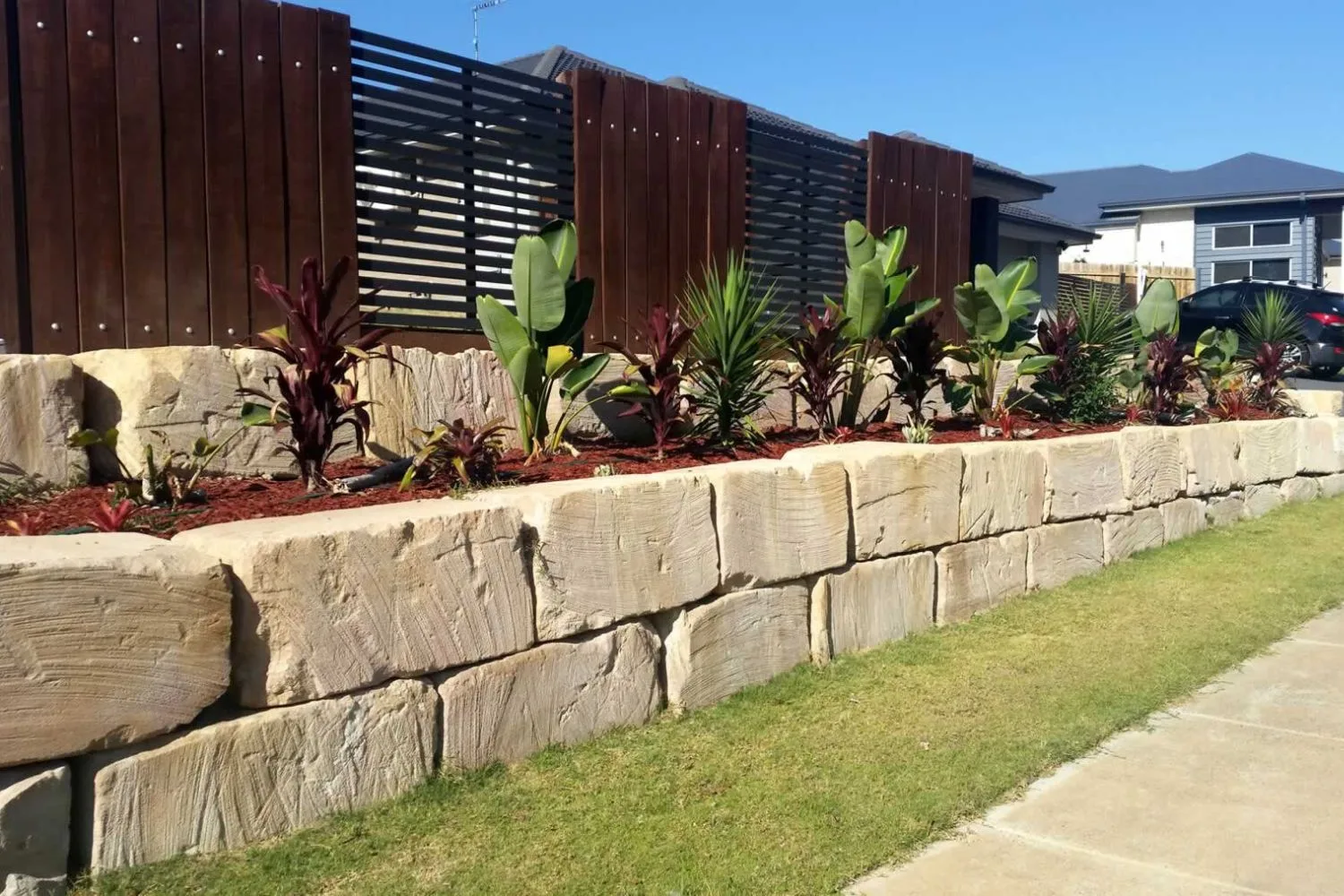 Sandstone block retaining wall along a front garden bed
