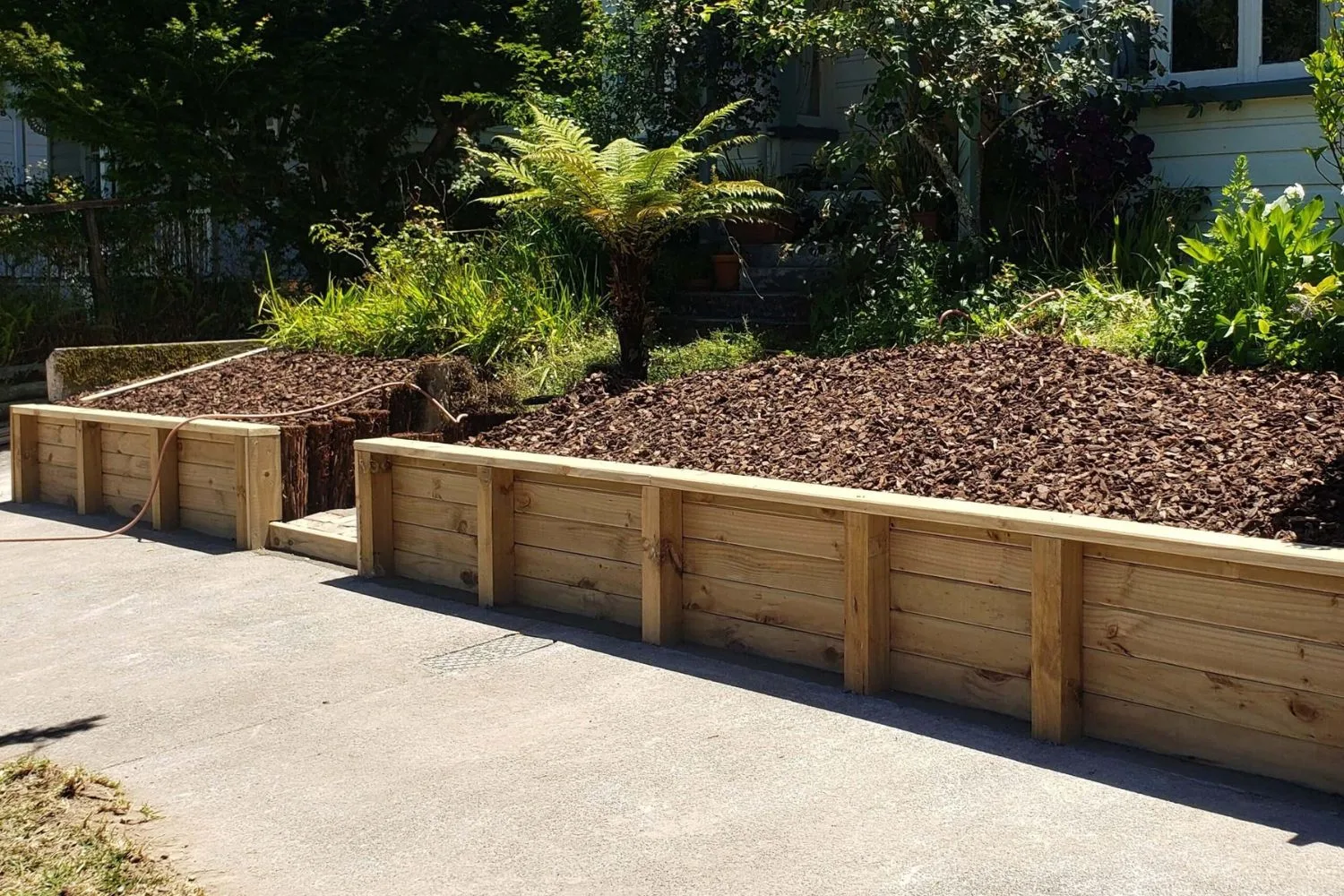 Timber retaining garden beds beside a driveway